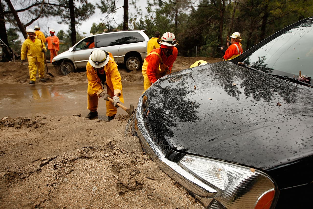 LA CANADA-FLINTRIDGE, CA - FEBRUARY 6: A crew of inmate firefighters from Azusa, California digs out cars that were swept away as debris flows damaged homes after heavy rains caused mudslides on February 6, 2010 in La Canada Flintridge, California. Large wildfires in 2008 and 2009 stripped the hills and mountains of vegetation, resulting in mud and debris flow danger as winter rains pass over foothill communities where thousands of people have been evacuated at times in recent weeks. The threat is particularly high near the San Gabriel Mountains above La Canada-Flintridge area which were denuded of natural flood-controlling vegetation by the 250-plus square mile Station. At least 40 homes have been severely damaged and 500 remain evacuated. (Photo by David McNew/Getty Images)