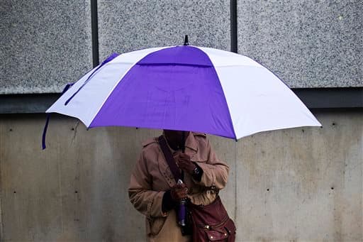 Una mujer se tapa de la lluvia con una sombrilla mientras espera su autobús en Birmingham.