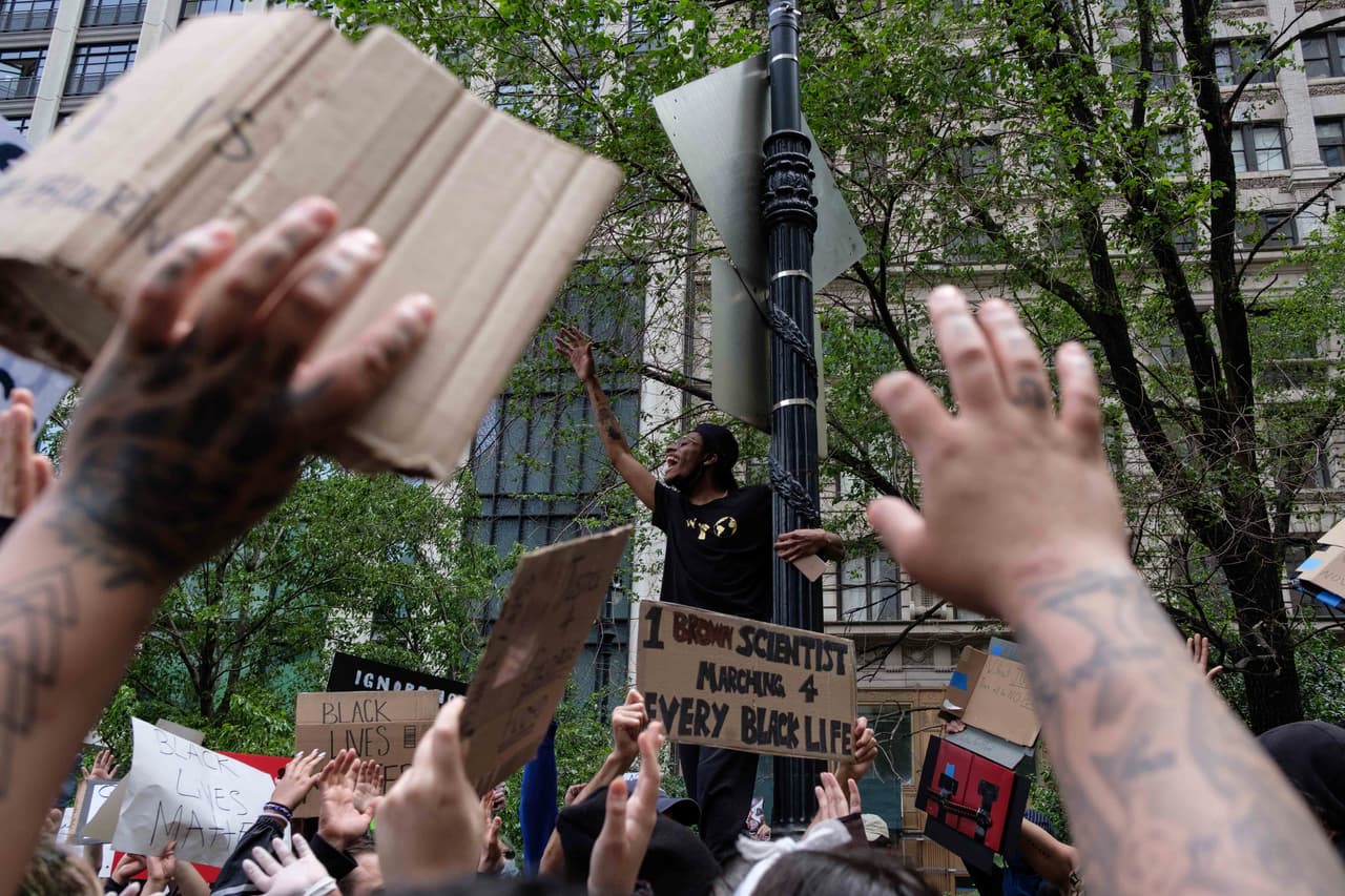 Con las manos levantadas, un grupo de personas se manifiestan cerca de Foley Square en Nueva York, el mediodía del martes.