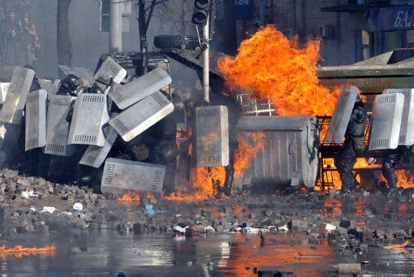 La policía ucraniana cercó hoy a los manifestantes en el corazón de las protestas opositoras de la plaza de la Independencia de Kiev (Maidán), tras una jornada en la que murieron 14 personas en los disturbios que estallaron en la capital. Víktor "Yanukóvich se ha convertido en un presidente sangriento", aseguró hoy el dirigente opositor Vitali Klitschkó en un llamamiento a los países democráticos para que intervengan en Ucrania y frenen la violenta confrontación. Según se acercaba la medianoche, los temidos Berkut, el destacamento antidisturbios, estrechaban el cerco en torno a los miles de manifestantes concentrados en el Euromaidán, bastión de las protestas desde el pasado 21 de noviembre. "Los extremistas de la oposición han cruzado la línea roja; matan a inocentes en la calles de la capital de Ucrania, vejan a mujeres, queman edificios y automóviles. Y si los disturbios continúan, nos veremos obligados a actuar con firmeza", rezaba el ultimátum del Servicio de Seguridad y el Ministerio del Interior de Ucrania. Advierten a los americanos que se queden dentro de las casas y de nuevo se sienten explosiones en la ciudad.