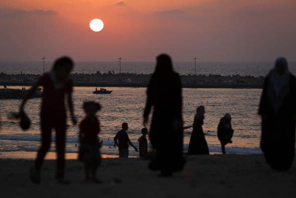 Familias palestinas caminan en la playa en la ciudad de Gaza después de una tregua de largo plaza entre Israel y Hamas.  