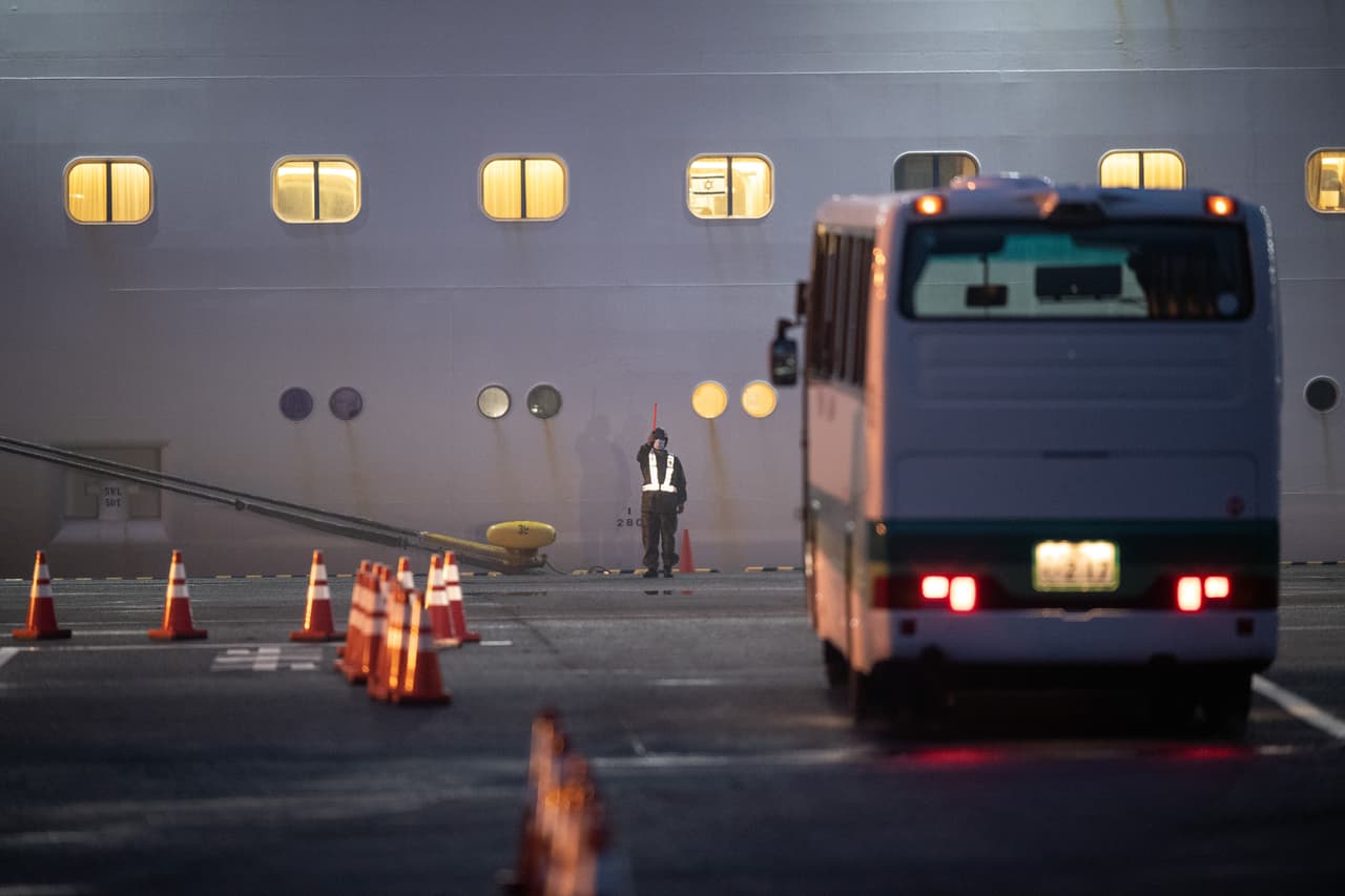 Un soldado de la Fuerza de Autodefensa de Japón dirige un autobús para estacionar cerca del crucero en cuarentena Diamond Princess en el muelle de Daikoku.