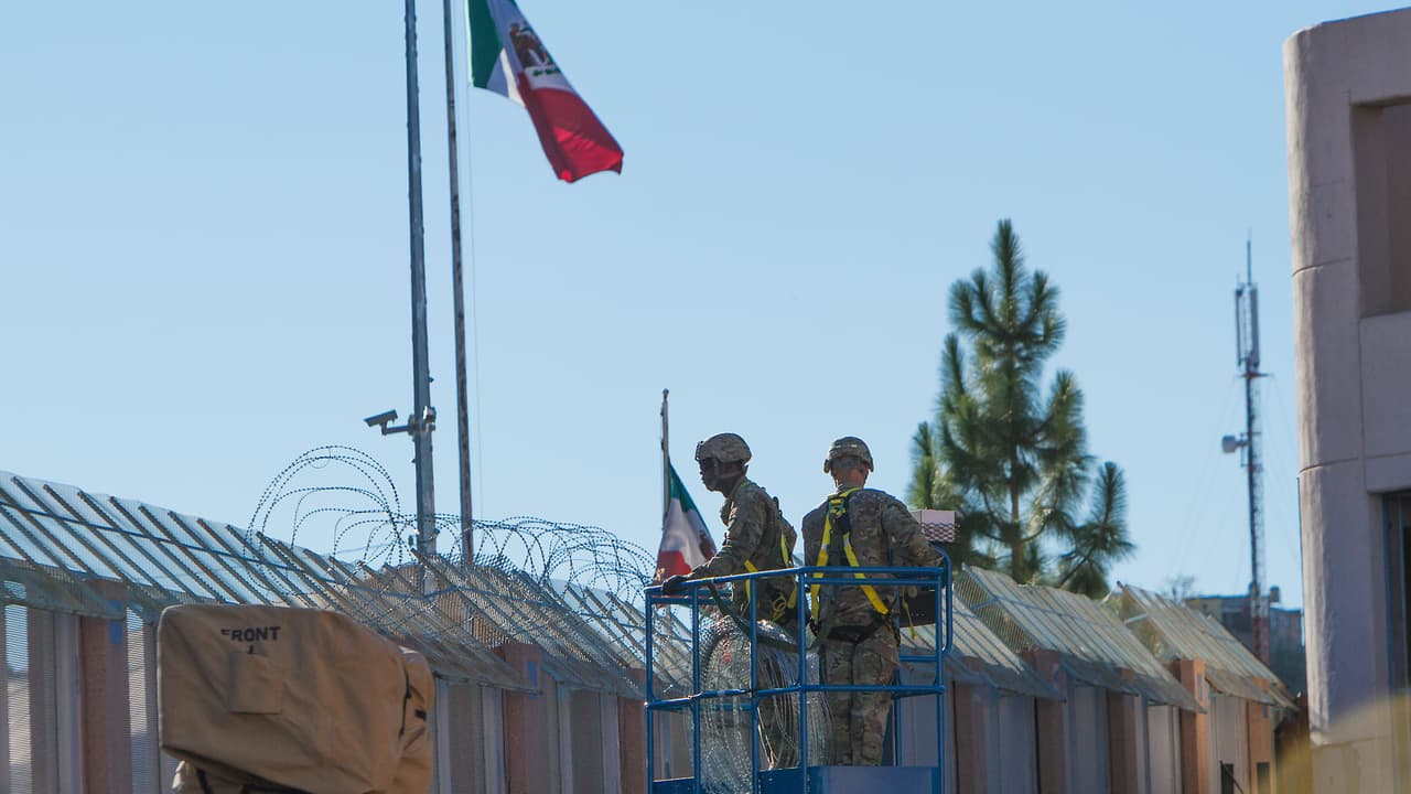 Desde un gato hidráulico dos soldados observan la ciudad de Nogales, Sonora, mientras colocan malla adicional en el centro de Nogales, Arizona.
