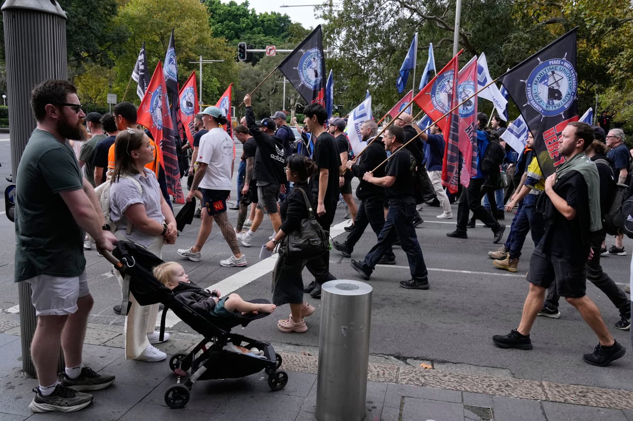 Una familia observa a la gente marchar para conmemorar el Día Internacional de los Trabajadores, también conocido como Primero de Mayo, en Sídney.
