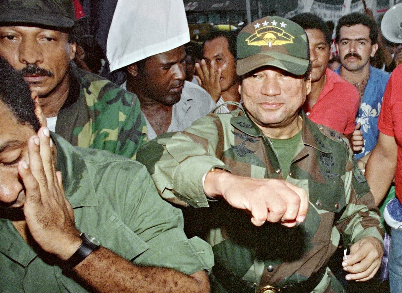 En febrero de 1988 se presentaron cargos contra el general panameño por narcotráfico en Tampa y Miami. Las presiones económicas de Estados Unidos se incrementaron, en un país que ya estaba en crisis. En una búsqueda por aparentar democracia, en mayo de 1989 se hicieron elecciones presidenciales. Denunciando un fraude, los partidarios del candidato opositor, Guillermo Endara Galimani, protestaron enérgicamente en las calles los resultados electorales. El gobierno anuló las elecciones por “injerencia extranjera” y las protestas fueron repromidas. Un nuevo presidente títere de Noriega fue declarado en en septiembre de 1989, Francisco Rodríguez. En la foto, Noriega saluda a algunos partiddarios el 2 de mayo de 1989, días antes de las elecciones que anuló.