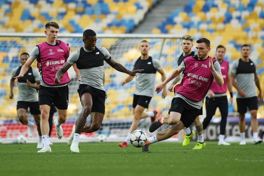 El holandés Georginio Wijnaldum (izq) y el escocés Andy Robertson disputan un balón en el entrenamiento en el estadio ucraniano, donde esperan combinarse efectivamente para la causa del club inglés.