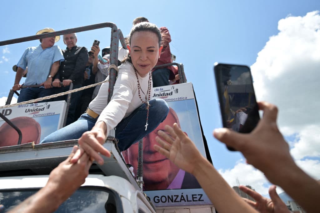 La líder opositora venezolana María Corina Machado se estira para saludar a sus partidarios durante una protesta convocada para que se reconozca la "victoria" electoral, en Caracas el 17 de agosto de 2024.
