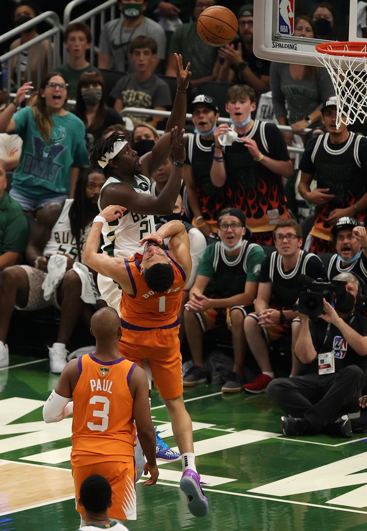 Devin Booker # 1 de los Phoenix Suns recibe un golpe en la barbilla mientras Jrue Holiday # 21 de los Milwaukee Bucks dispara durante la primera mitad del Juego Cuatro de las Finales de la NBA.