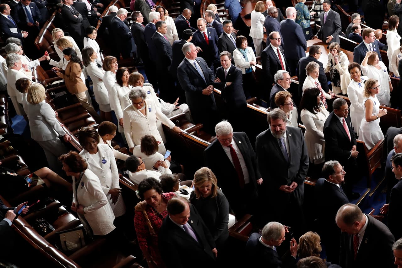 Congresistas del Partido Demócrata vestidas de blanco, toman asiento antes del comienzo del evento.