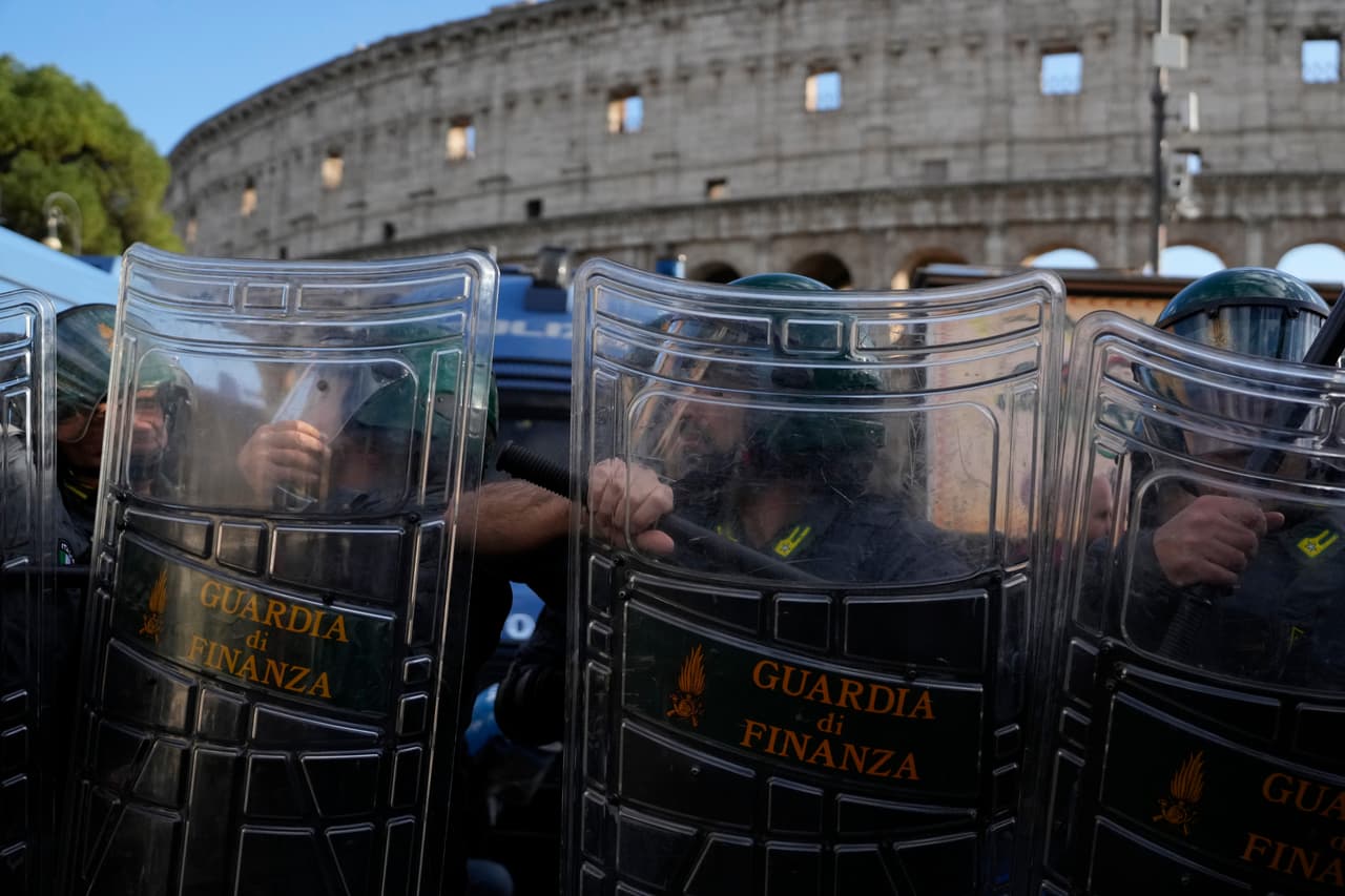 Policías antidisturbios italianos observan a activistas pacifistas que se manifiestan contra el rearme y la participación de Italia en guerras frente al Coliseo en Roma, el sábado 24 de octubre de 2026.