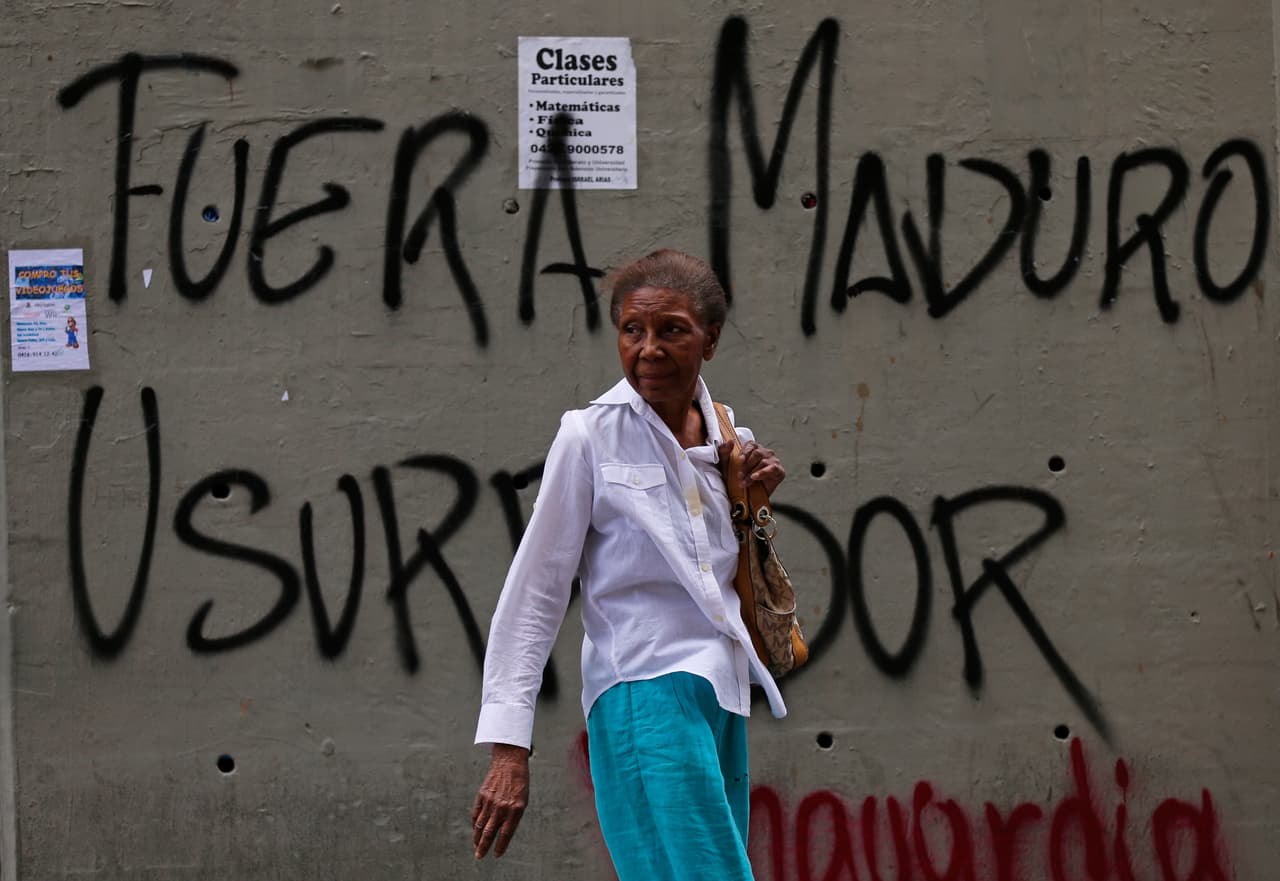 Una mujer camina frente a un muro con el mensaje: "Fuera Maduro usurpador" en referencia al presidente Nicolás Maduro en Caracas, Venezuela, el jueves 24 de enero de 2019. (AP Foto/Fernando Llano)