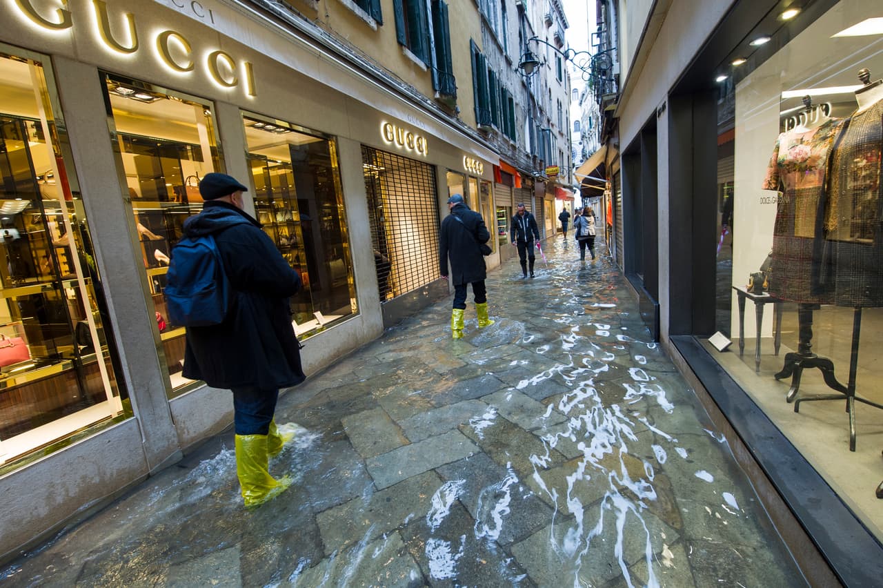 VENICE, ITALY - NOVEMBER 19: People walk in one of the main shopping streets flooded during bad weather and high waters on November 19, 2013 in Venice, Italy. Venice will be affected by the high water for the next few days due to the passage of Cyclone Cleopatra that hit the Italian island of Sardinia causing devastating flooding, which has left at least 17 dead. (Photo by Marco Secchi/Getty Images)