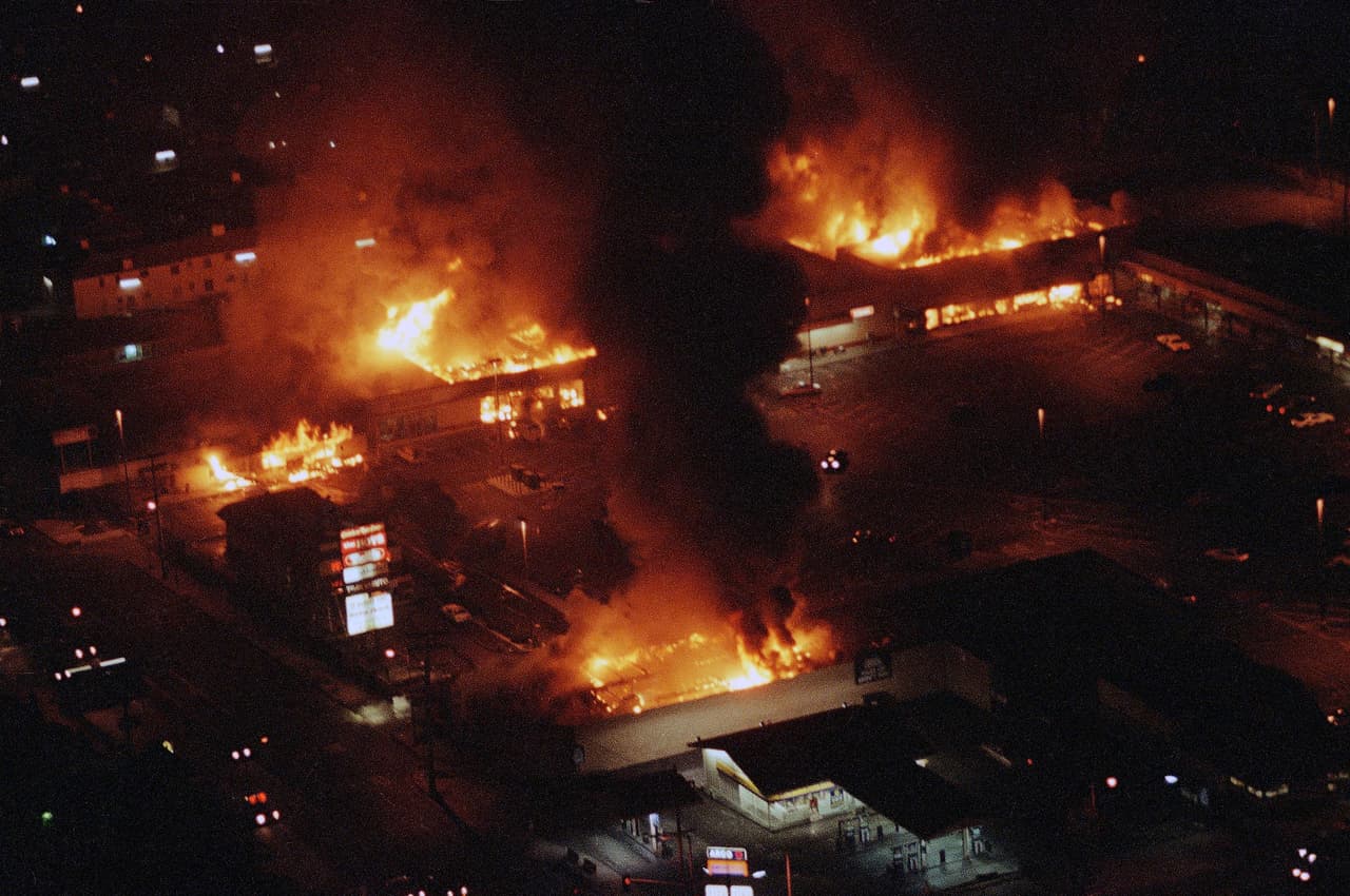 Varios locales en una plaza comercial en Sur Los Ángeles ardían sin control en el segundo día de disturbios en la primavera de 1992.