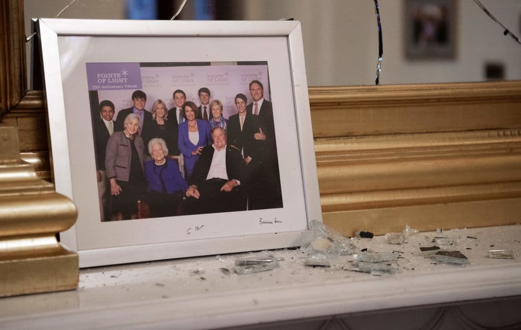 Cristales rotos junto a un retrato de Nancy Pelosi junto al expresidente George H. W. Bush. La foto se encontraba dentro de su oficina en el edificio.