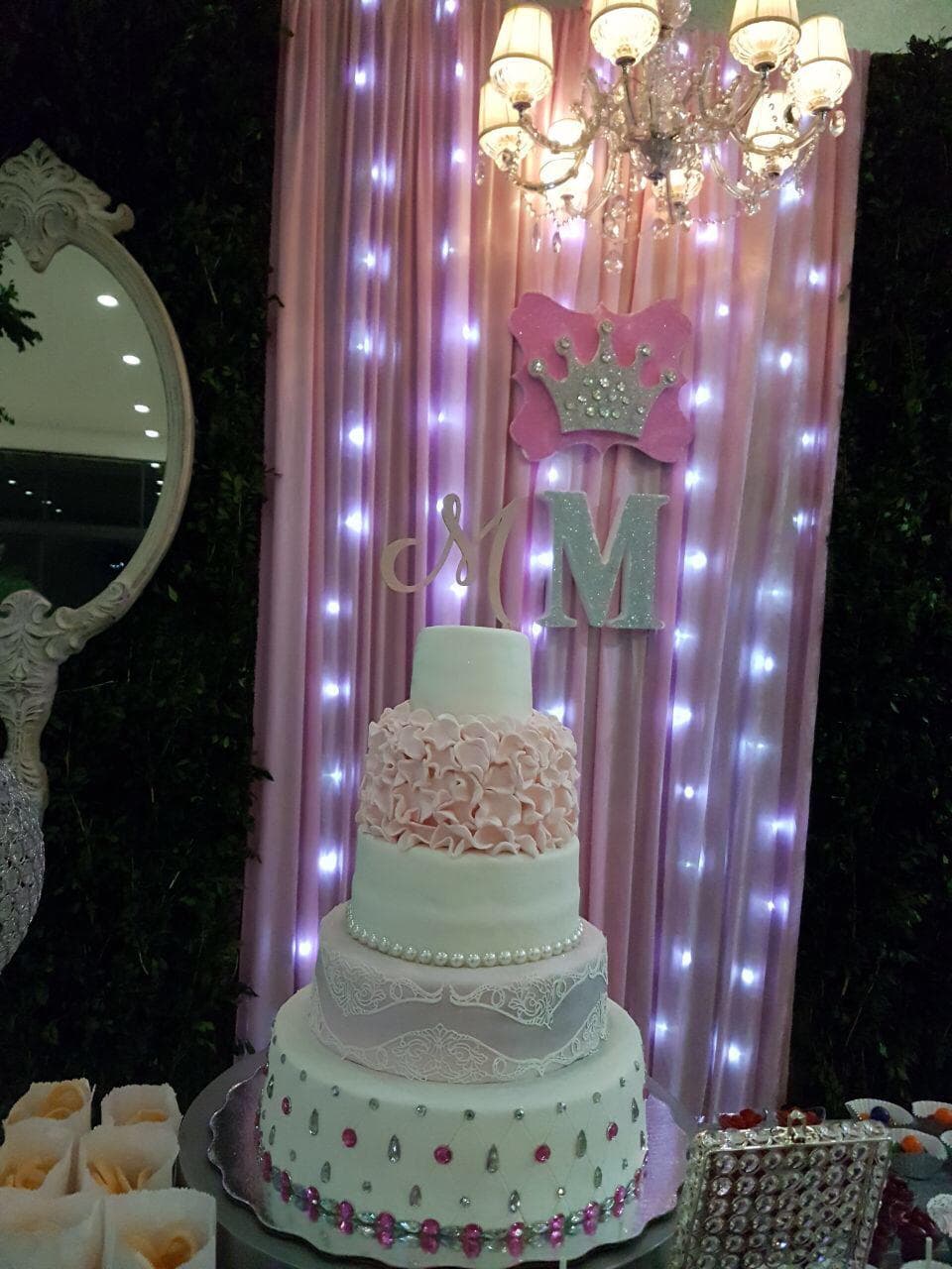 No podía faltar el elegante pastel de cinco pisos, diseño exclusivo que en la parte de arriba destacaba con una letra M, al igual que en todos los adornos de las paredes y mesas.