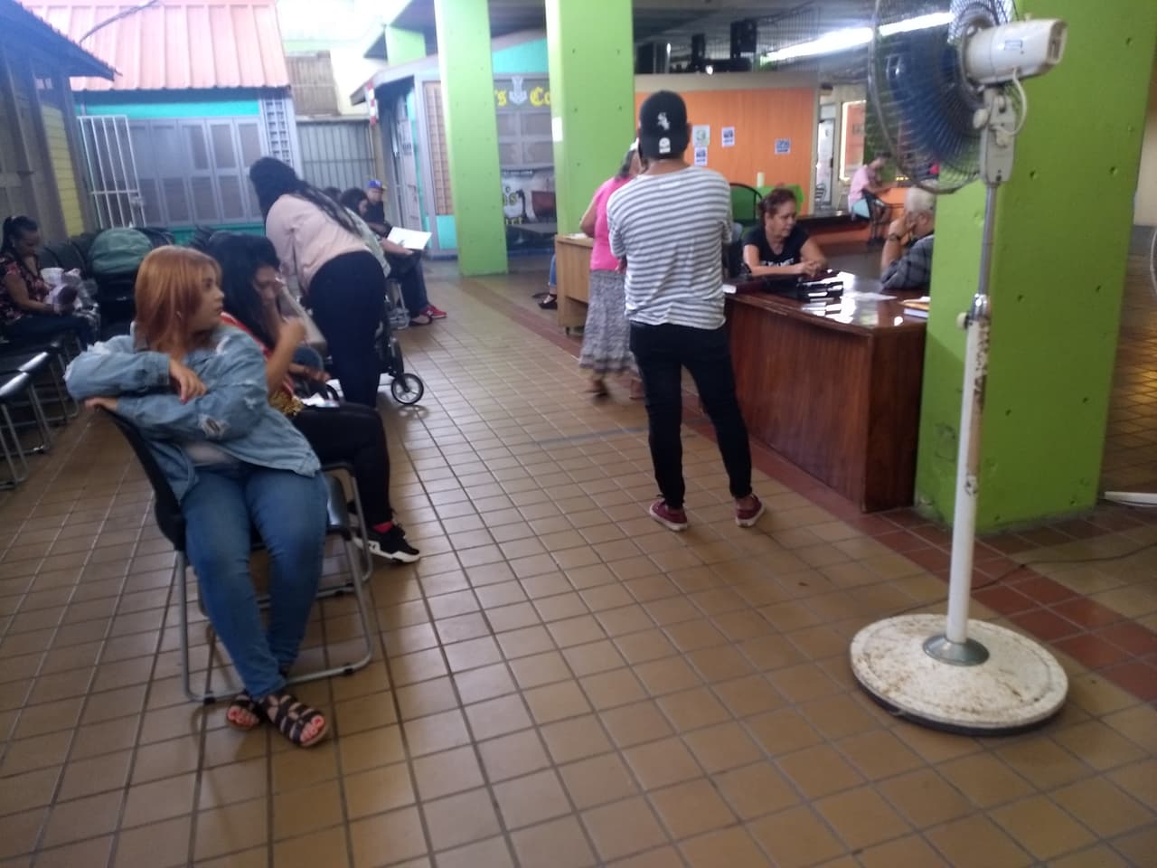 La sala de espera del Registro Demográfico de Caguas está en medio de la Plaza del Mercado, sin aire, entre criaderos de mosquitos y animales realengos. 
<br>