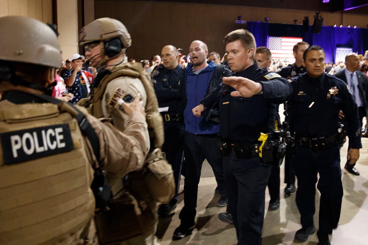 A man is escorted by law enforcement officers moments after Republican presidential candidate Donald Trump was rushed offstage by Secret Service agents during a campaign rally in Reno, Nev., on Saturday, Nov. 5, 2016. (AP Photo/ Evan Vucci)