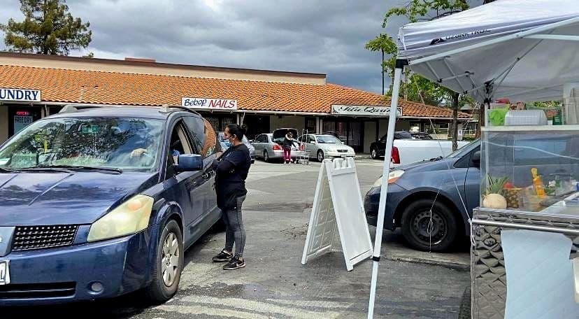 Doña Teresa atiende a un cliente desde su puesto de frutas, que abrió en medio de la pandemia de coronavirus.