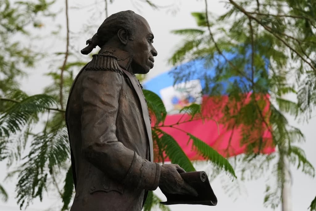 Una bandera haitiana ondea detrás de una estatua de Toussaint Louverture, uno de los héroes de la Guerra de Independencia. Al menos, 350,000 haitianos se enfrentan a una posible deportación con la inminente finalización del Estatus de Protección Temporal.