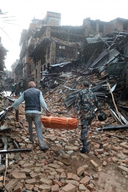 Un voluntario y un miembro de las fuerzas de seguridad cargan casas de campaña para desplegarlas en las calles.