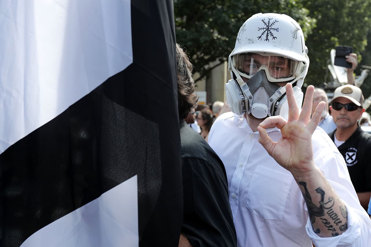 Un manifestante hace un símbolo identificado con los simpatizantes del movimiento supremacista racial durante el mitin convocado por neonazis en Charlottesville, el 12 de agosto de 2017. Después de que uno de los participantes arrollara a una multitud que se enfrentó a la protesta, Trump dijo que los dos lados había "gente muy buena".