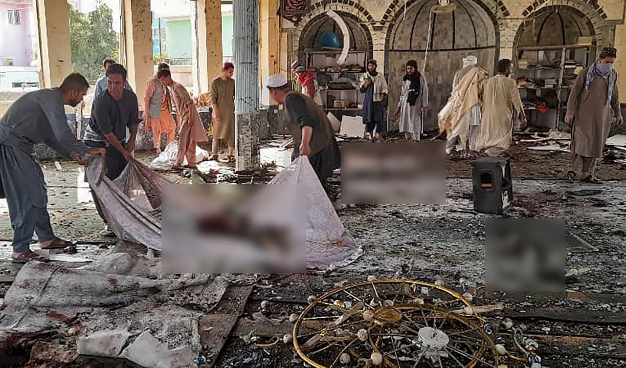 Varios hombres recogen los cuerpos de las víctimas de un ataque con bomba en una mezquita chií, en la provincia de Kunduz, al norte de Afganistán. Al menos 100 personas resultaron muertas o heridas, indicaron funcionarios a la agencia AP.