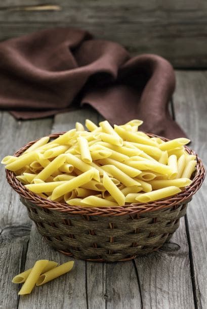 Fideos ziti salteados con jugo de naranja y espárragos.