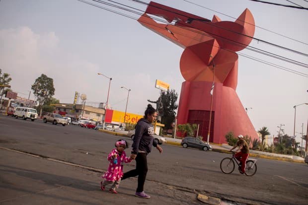 Personas caminando cerca de El Coyote, una escultura monumental en la parte más vieja de la ciudad Nezahualcóyotl.