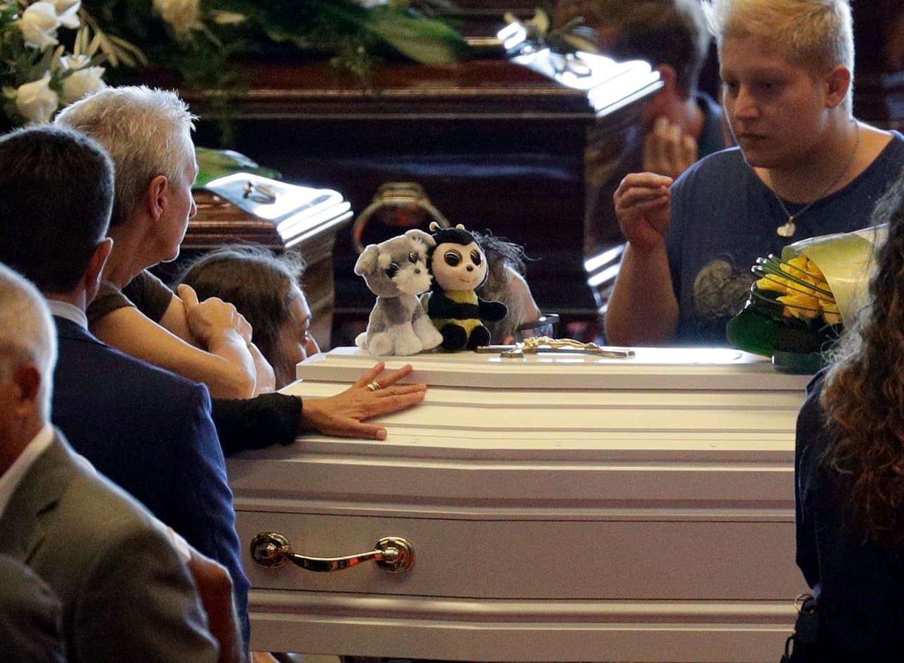 Stuffed toys are placed on a small white coffin of a child ahead of a funeral service for some of the victims of a collapsed highway bridge, in Genoa's exhibition center Fiera di Genova, Italy, Saturday, Aug. 18, 2018. Saturday has been declared a national day of mourning in Italy and includes a state funeral at the industrial port city's fair grounds for those who plunged to their deaths as the 45-meter (150-foot) tall Morandi Bridge gave way Tuesday. (AP Photo/Gregorio Borgia)