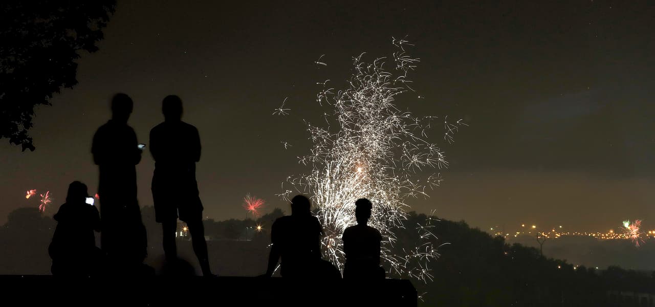 Personas contemplan los fuegos artificiales desde un punto elevado del Liberty Memorial en Kansas City, Missouri.