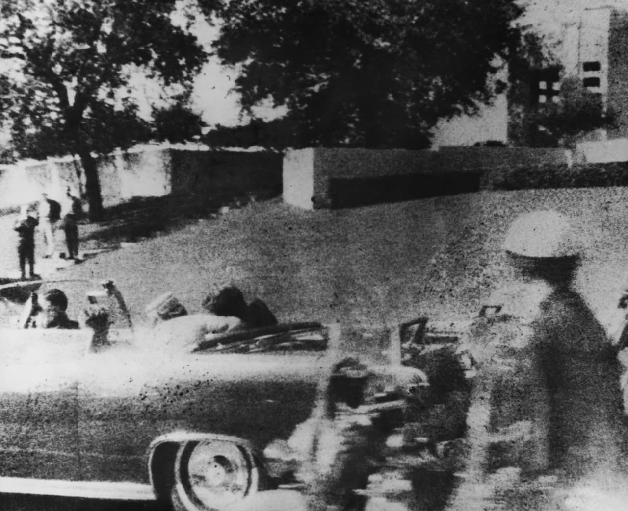 En esta se observa al presidente John F. Kennedy herido de bala y la primera dama Jacqueline va sosteniéndolo. El ex marín Lee Harvey Oswald fue quien asesinó al presidente Kennedy el 22 de noviembre de 1963. En este enlace podrás ver un video del sitio de donde Lee Harvey Oswald disparó contra el presidente.