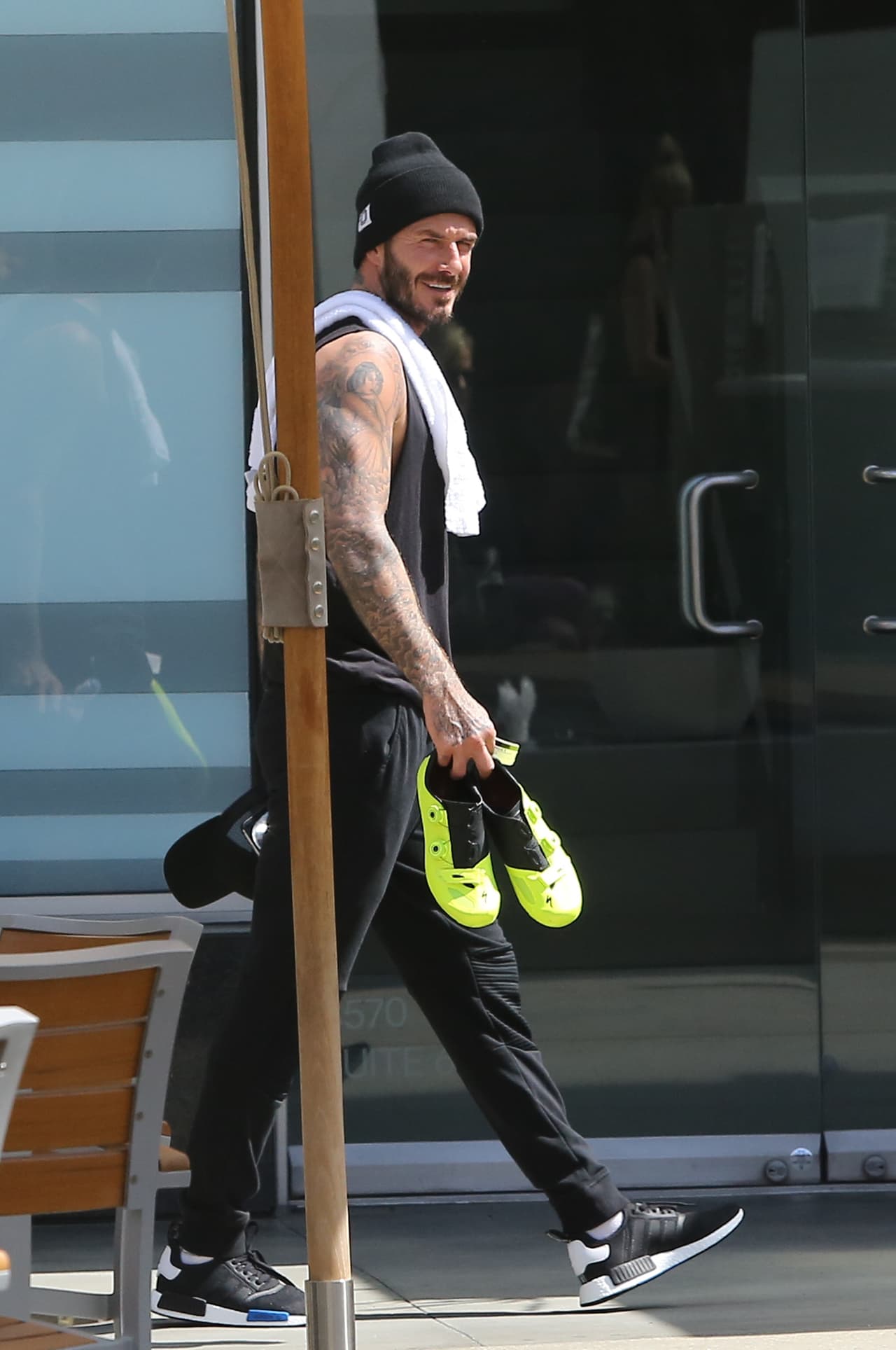 Cargando otros tenis y con su toalla al hombro.