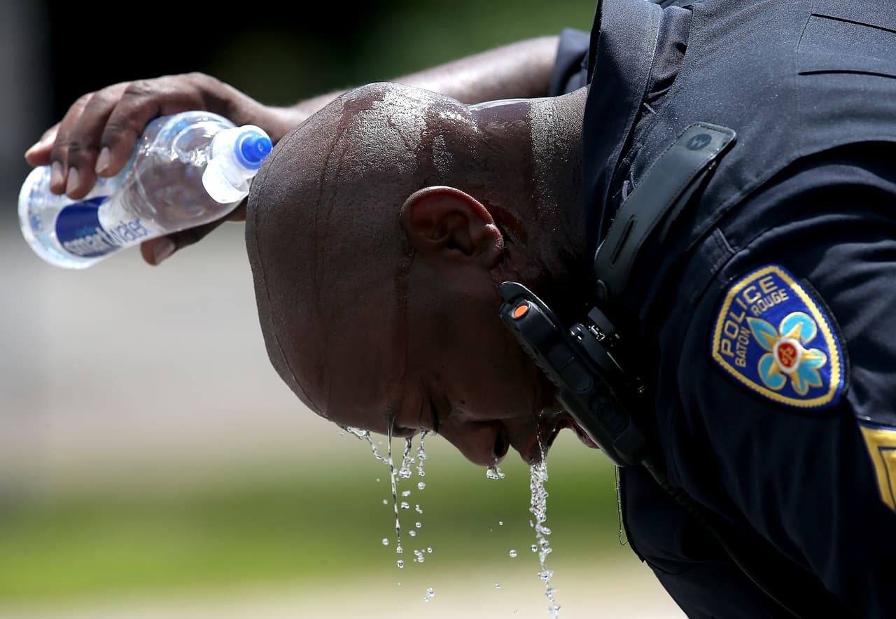 Un policía de Baton Rouge vierte agua sobre su cabeza tras realizar un operativo en los alrededores del lugar del tiroteo.