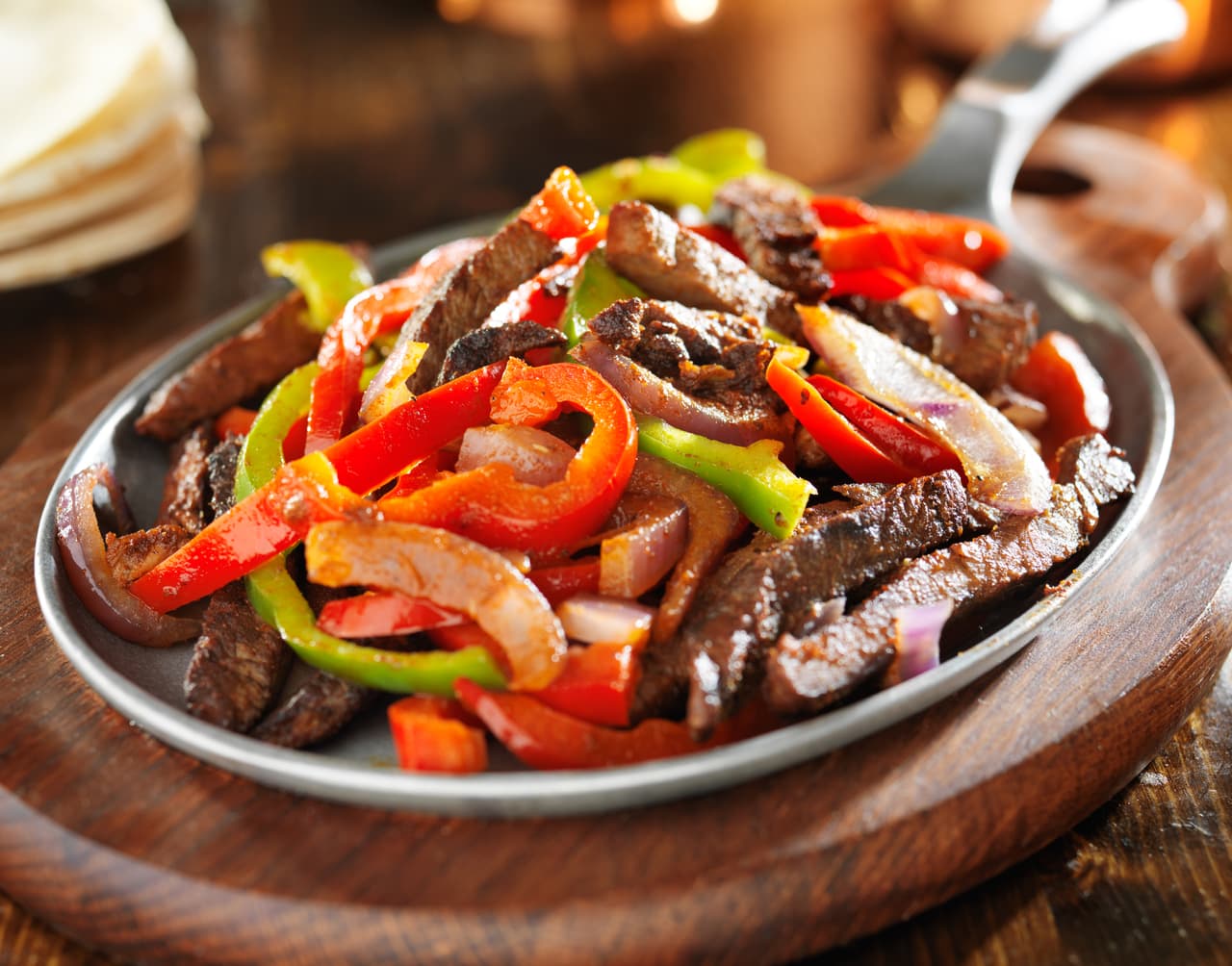 <b>Fajitas.</b> Es un platillo de inspiración mexicana nacido al norte de la frontera. Como el chili, su origen pudo haber estado en los cocineros de los vaqueros texanos durante las faenas con el ganado. 
<br>
<br>La receta original incluye fajas o tiras de carne de res fritas con pimientos y cebollas, y servidas con tortillas de harina de trigo. Las versiones modernas, que ganaron popularidad a finales del siglo XX, están hechas también con pollo, cerdo, camarones e incluso tofu, y generalmente se sirven en un recipiente de metal muy caliente.
<br>