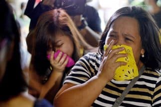 Mujeres lloran en las afueras de la fábrica de zapatos en Valenzuela, Filipinas, donde murieron al menos 72 trabajadores.