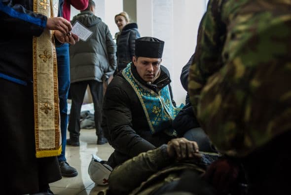 Un sacerdote asiste a uno de los manifestantes caídos en las protestas del jueves.