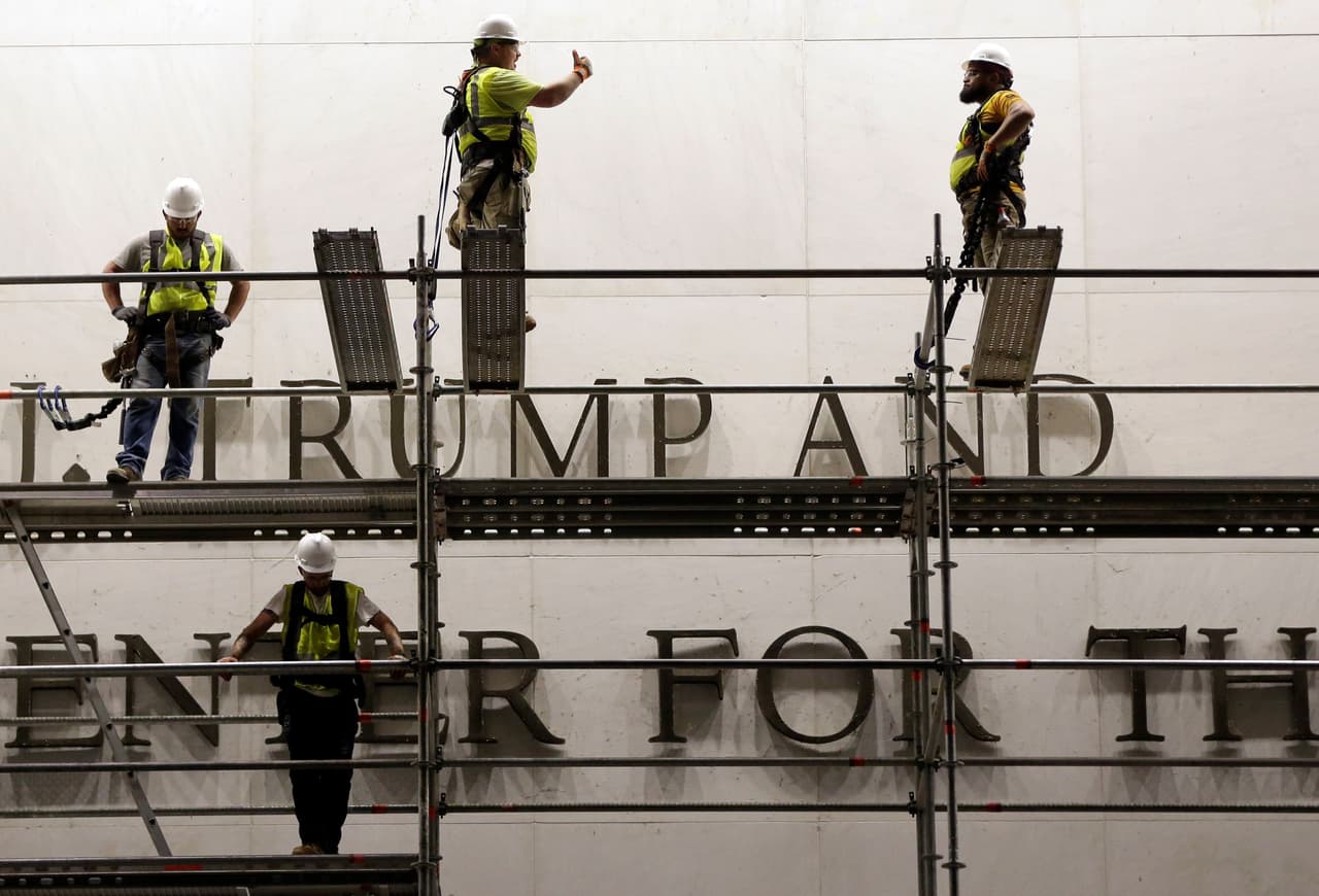 Trabajadores se encuentran frente al letrero del Centro John F. Kennedy.