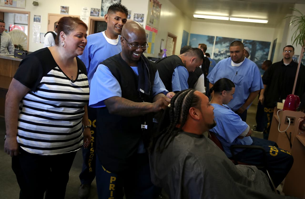 La instructora de Cosmetología Carmen Shehorn (izquierda), observa mientras el reo Rodney Williams (centro), le hace trenzas a su compañero de prisión Víctor Moreno, der., durante su clase de cosmetología en Valley State.