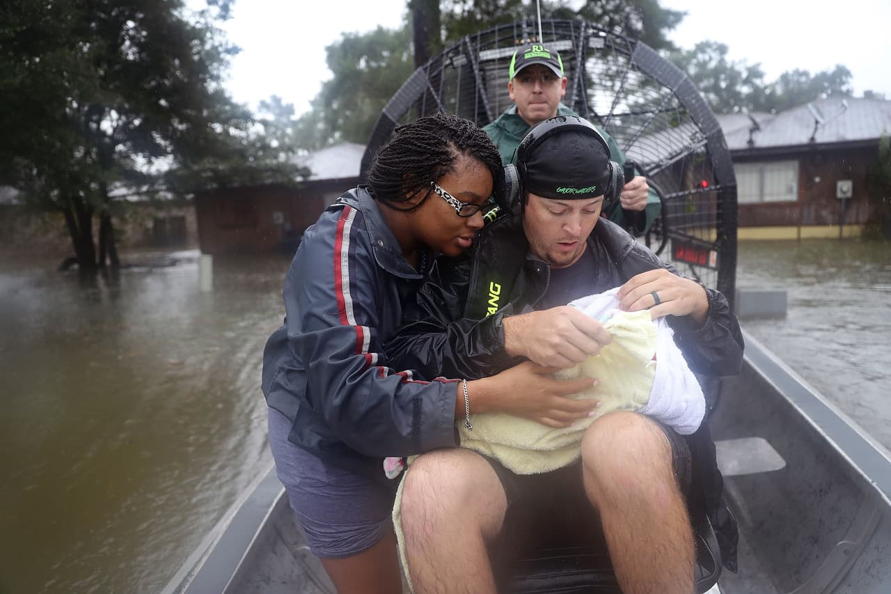 Shardea Harrison se pone a salvo junto a su bebe de tres semanas. Fueron recatados por Dean Mize y Jason Legnon en su hidrodeslizador de una calle inundada en Houston.