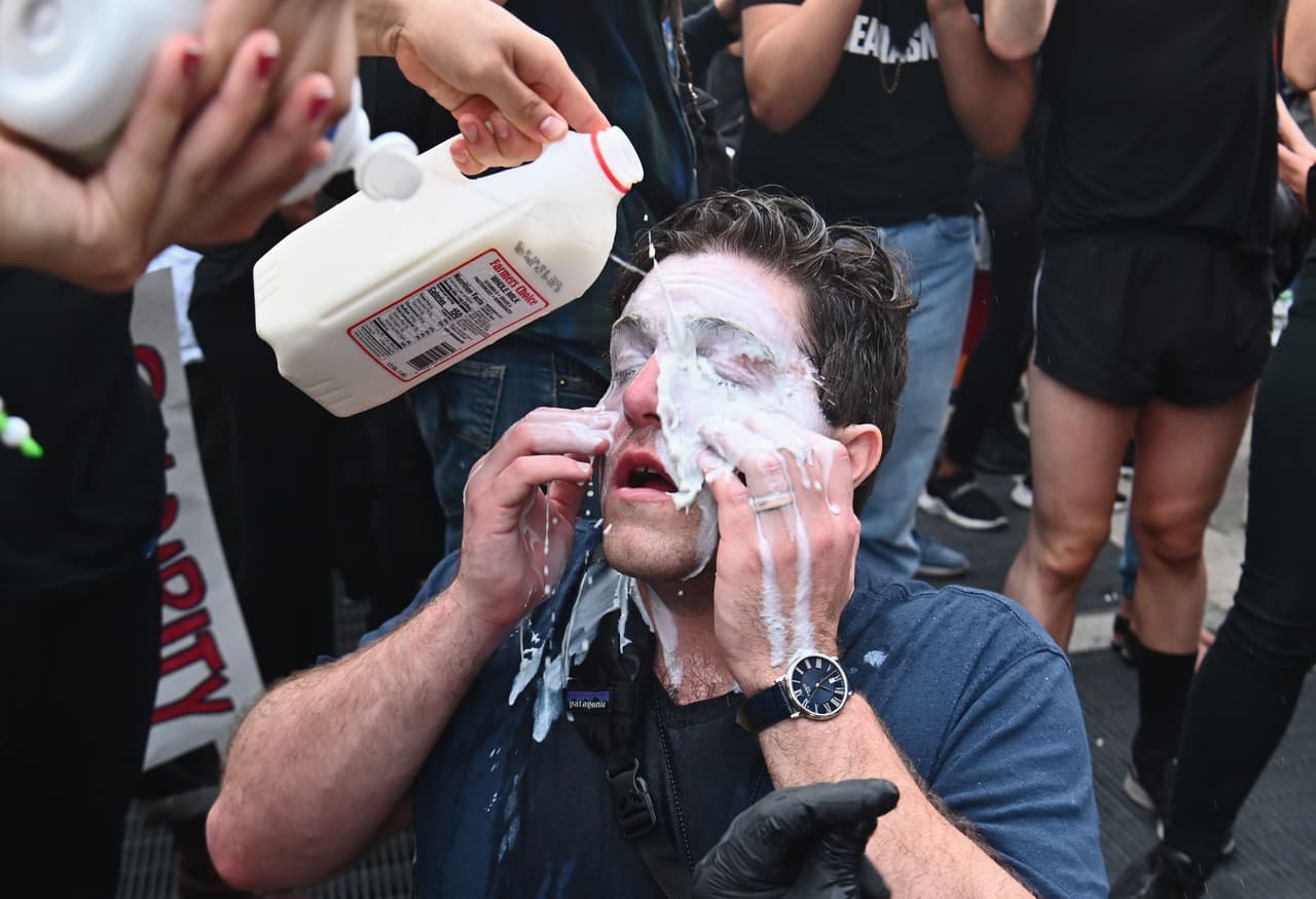 Un protestante se echa leche en los ojos después de que lo rociaran con gas pimienta.