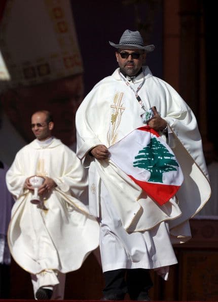 Un sacerdote libanés sostiene la bandera de su país, tras la celebración de la misa del papa Francisco en Jordania.