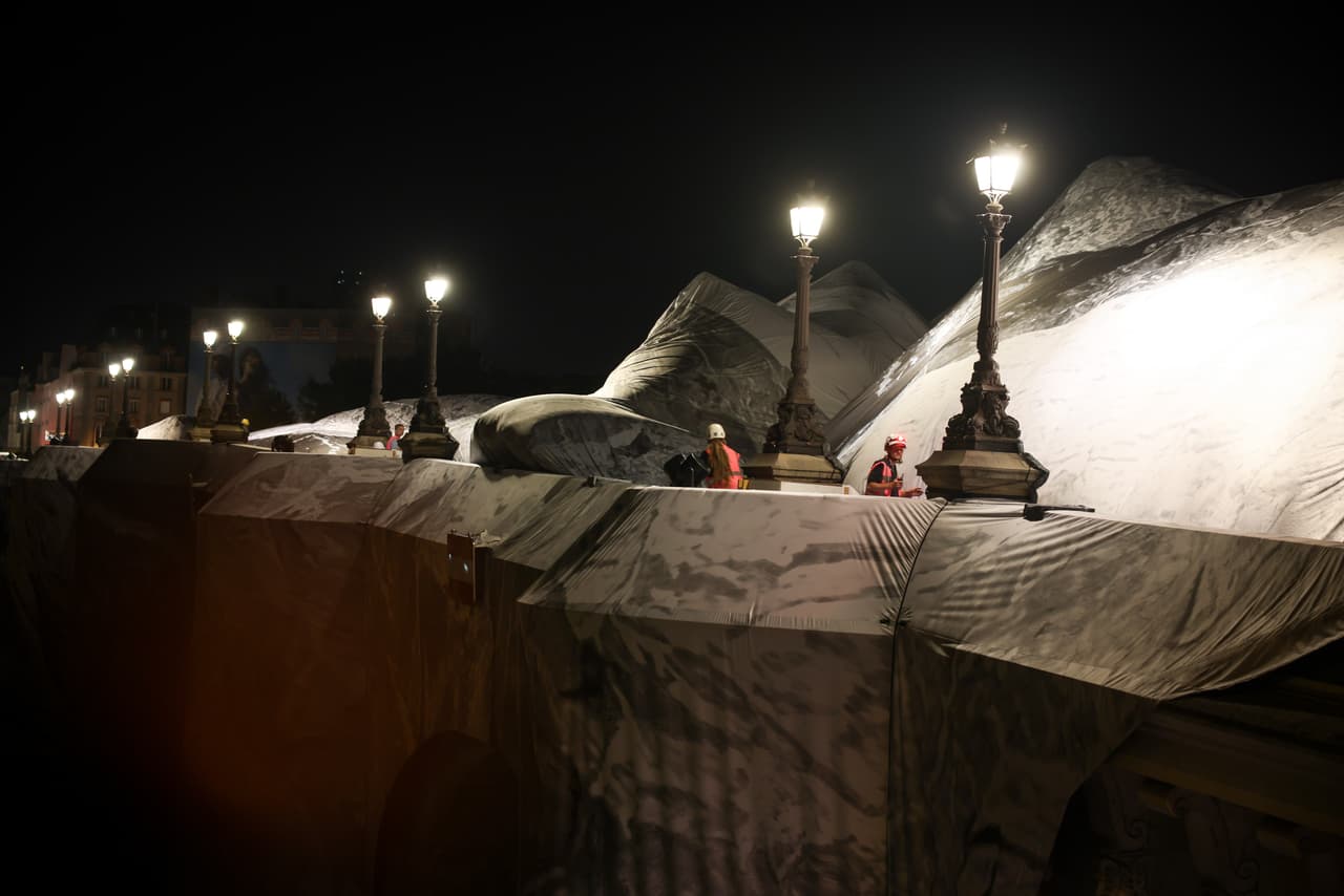 Un trabajador supervisa el inflado de "La Cueva del Pont Neuf", obra del artista callejero francés JR, en el puente Pont Neuf de París, el miércoles 20 de mayo de 2026, antes de su inauguración gratuita al público del 6 al 28 de junio. (Foto AP/Thomas Padilla)