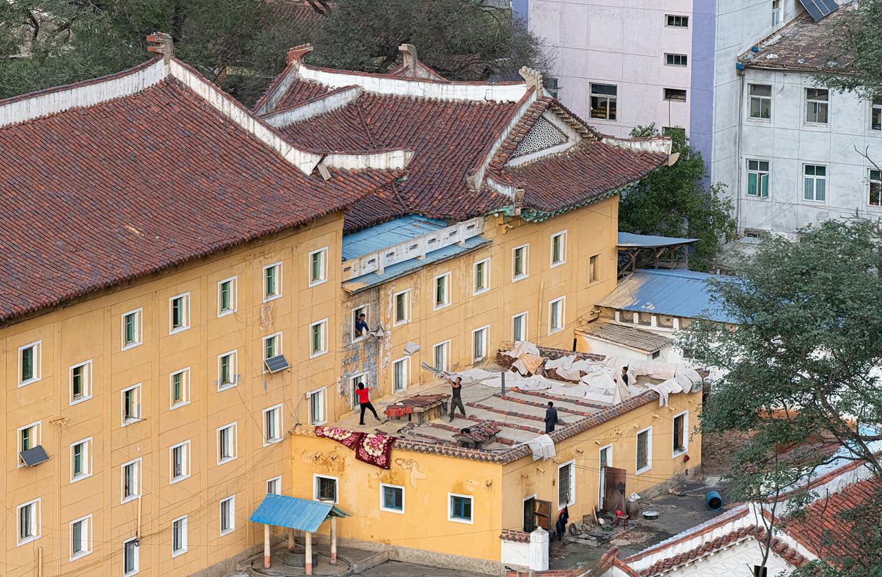 “A una hora y media de Pyongyang se encuentra Sariwon, la capital de la provincia de Hwanghae del Norte.
<br>
<br>Ted subió la colina más alta del distrito y fue recibido con una vista de este edificio amarillo brillante, presumiblemente un hotel”, explica Daylight Books.
<br>