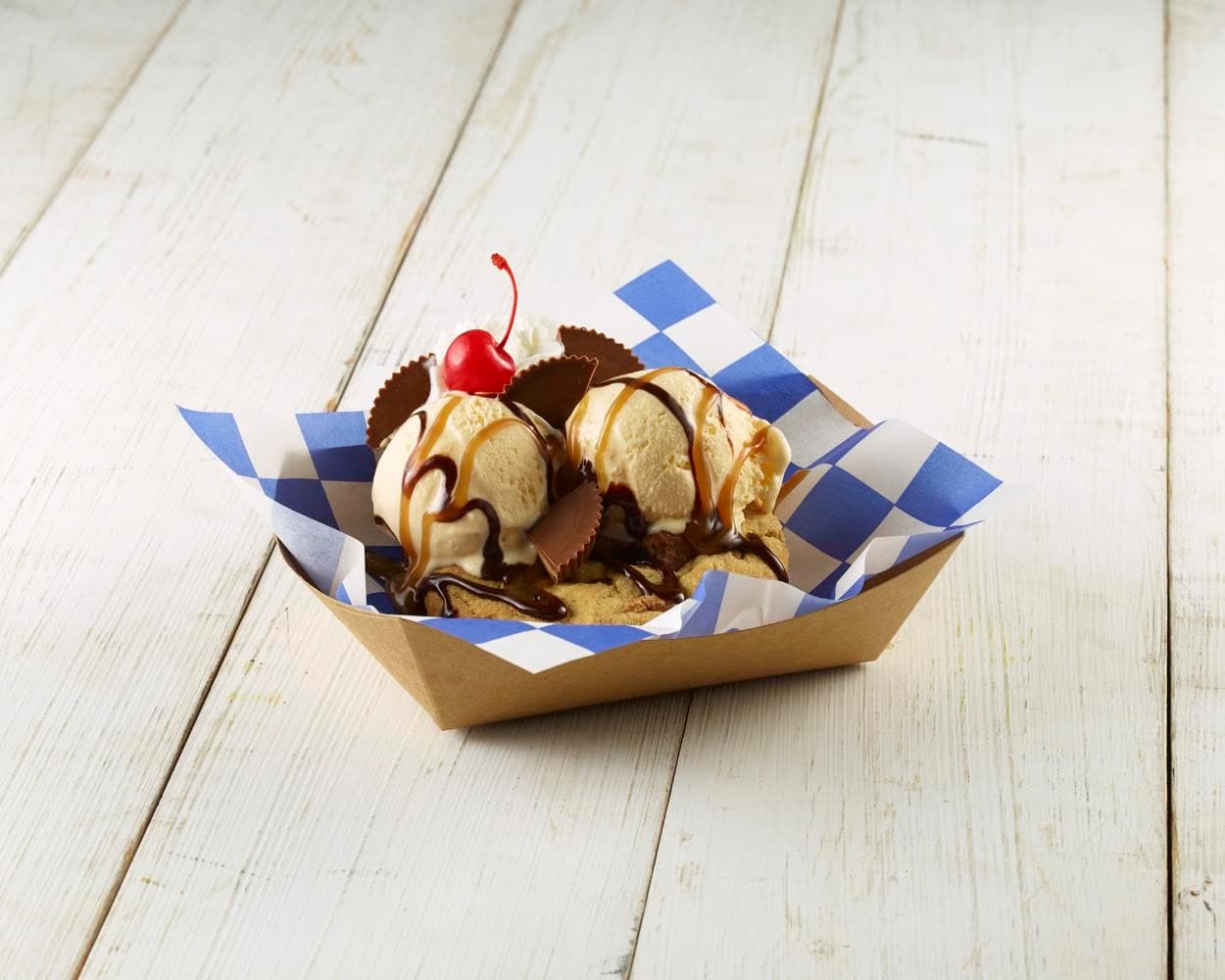 PEANUT BUTTER CUP SNOOKIE - Galleta caliente y fresca de mantequilla de maní horneada con helado de vainilla adornada con caramelo y llovizna de chocolate, crema batida y una cereza.