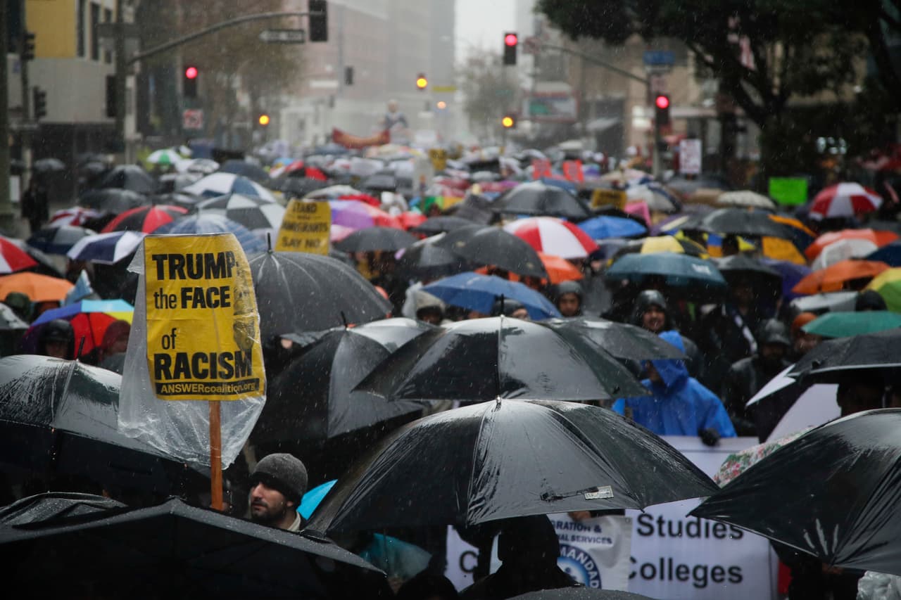 “Trump el rostro del fascismo”, dice una pancarta que sobresale de un río de sombrillas.