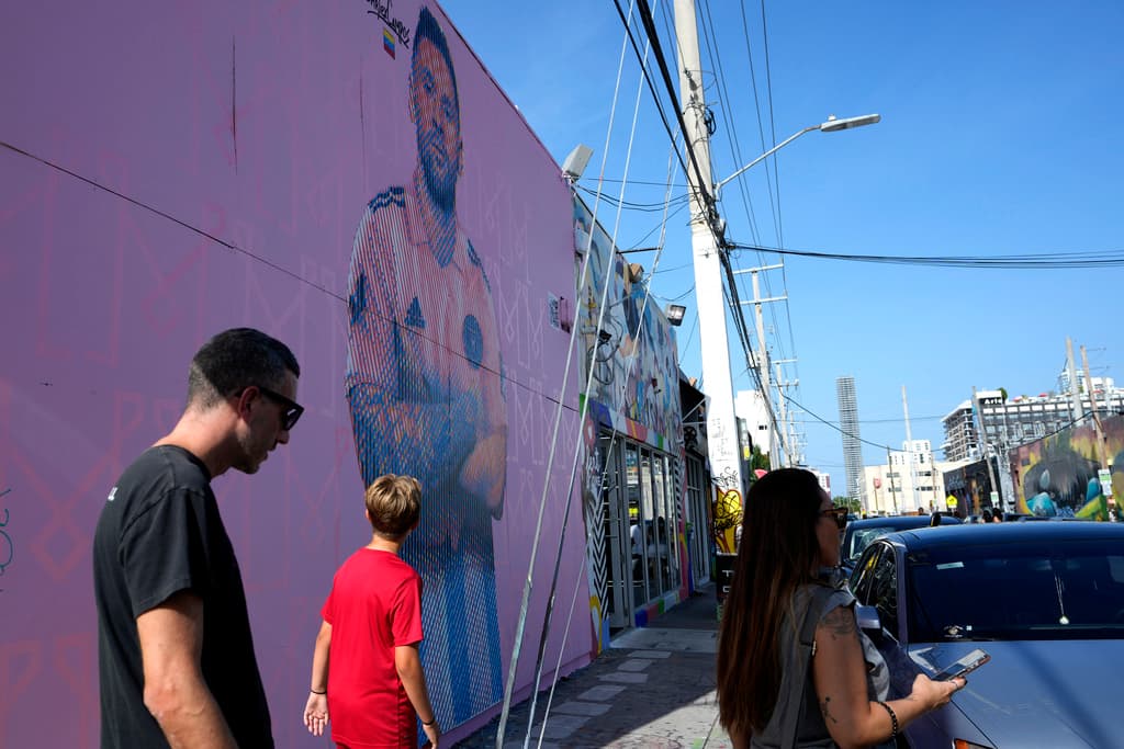 Murales, hamburguesas, cervezas y vallas publicitarias son solo un puñado de ejemplos que muestran la euforia que genera Messi en el sur de la Florida y cómo será recibido. Hacia el sur, en el
<b>vecindario de Wynwood</b>, un área vecina al centro de Miami conocida por sus almacenes convertidos en galerías de arte y grafitis en las paredes, otros artistas han pintado murales de Messi.
<b>En la imagen la gente pasa frente a un mural del artista Arlex Campos.</b>