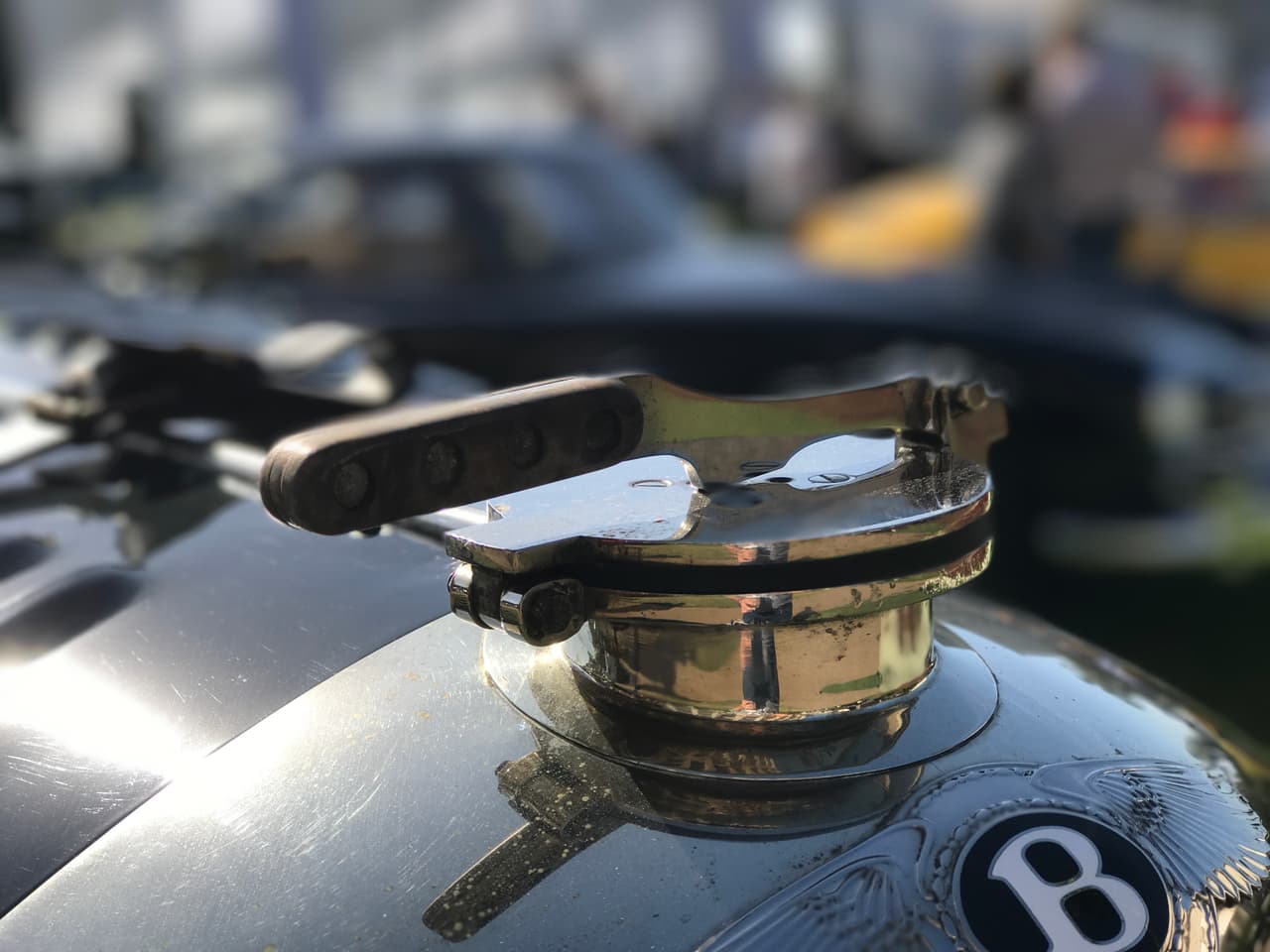 Este
<b>Bentley 4 1/2 litros Le Mans Sports 'The Bobtail' de carreras de 1928</b> no tiene ningún uso para adornos en su capó. Su emblema de capó es simplemente un mecanismo para abrir el radiador. Estos adornos comenzaron a aparecer para reemplazar a estos mecanismos y a los medidores de temperatura para el agua del radiador.