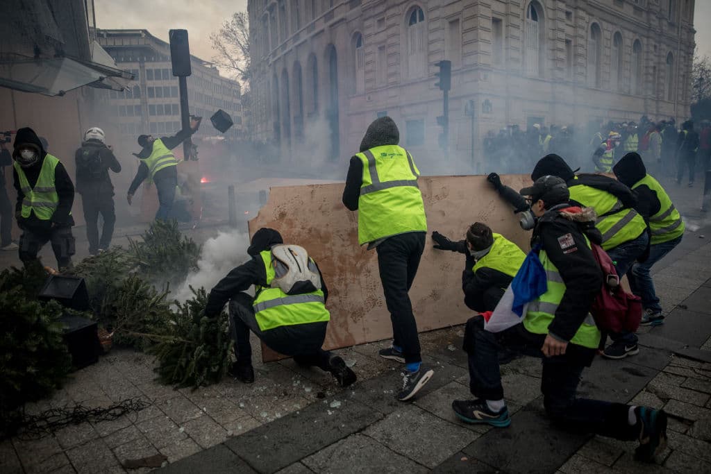 Manifestantes se protegen detrás de una barricada durante la manifestación del 8 de diciembre.
