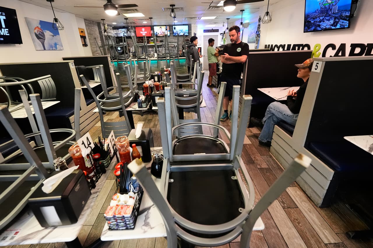 Dor Offer, propietario del Café Bistro, consulta el pronóstico del tiempo en su teléfono mientras cierra su restaurante ante la llegada del huracán Isaias a Pensacola Beach, Florida, el viernes 9 de octubre de 2026.