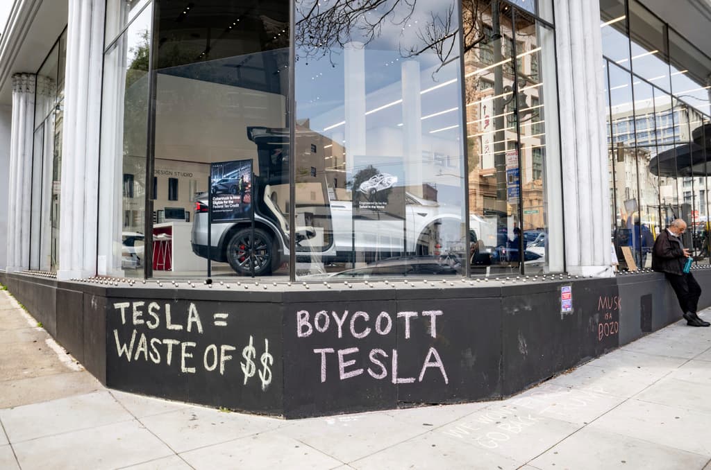 Graffiti con tiza se muestra en el exterior de un concesionario de Tesla durante una manifestación en San Francisco, el sábado 15 de marzo de 2025. (AP Foto/Josh Edelson)